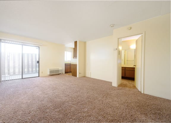 a bedroom with a large window and a door leading to a kitchen at Park Columbia Apts, Hemet, 92544