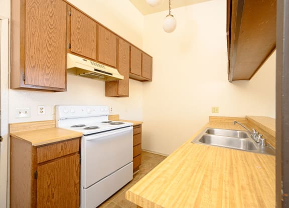 a kitchen with wooden cabinets and white appliances at Park Columbia Apts, Hemet, CA