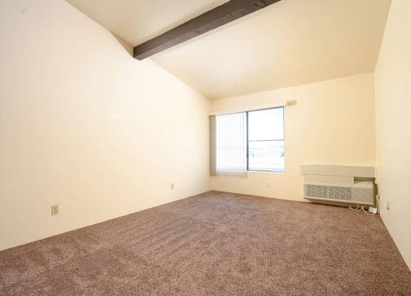 a bedroom with carpeted floors and a large window at Park Columbia Apts, California, 92544
