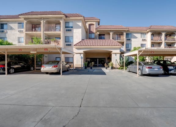 an empty parking lot in front of an apartment building with cars parked at Flamingo Garden Senior Apts, El Monte California