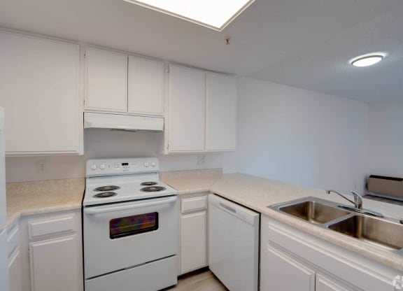 a kitchen with white appliances and white cabinets at Flamingo Garden Senior Apts, El Monte