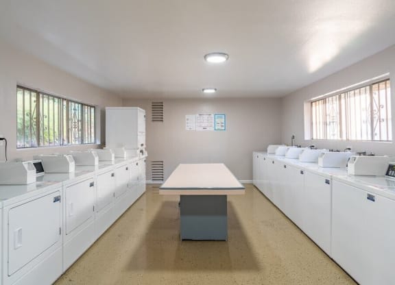 an empty kitchen with white cabinets and a table at North View Terrace, Montebello, CA