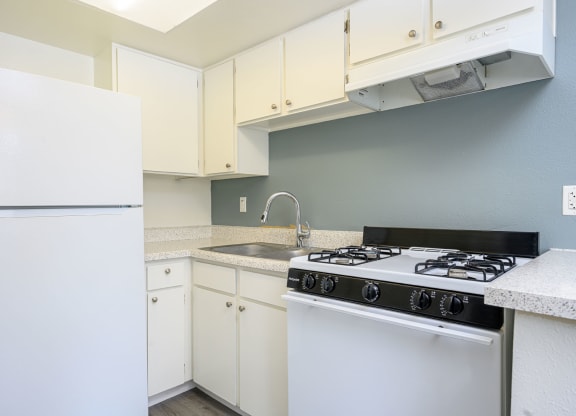 a kitchen with white cabinets and a white stove top oven at Sagewood Gardens Senior Apartments, Hacienda Heights