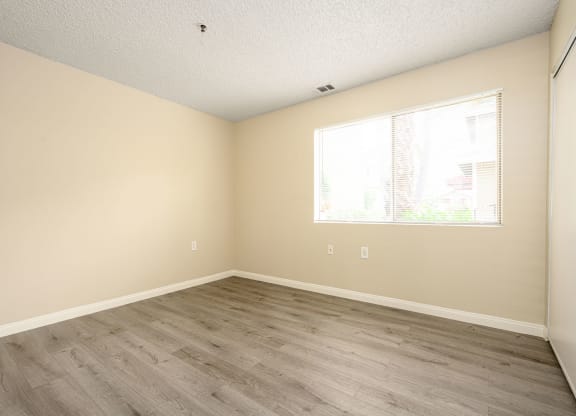 a bedroom with hardwood floors and a large window at Sagewood Gardens Senior Apartments, California