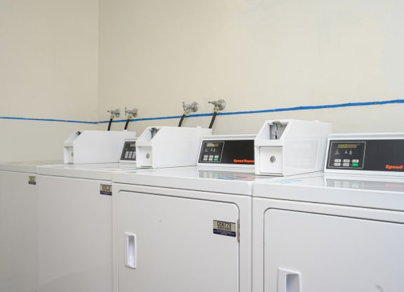 a row of washers and dryers in a laundry room at Villa Hemet, Hemet, CA