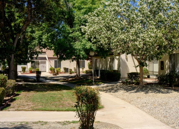 a building with a sidewalk and trees in front of it at Villa Hemet, Hemet, CA