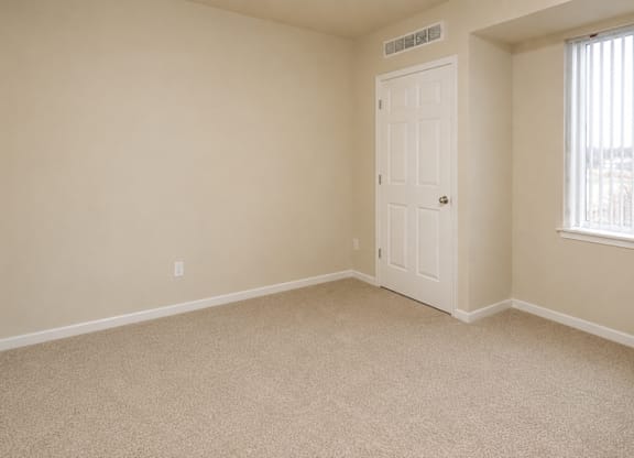 A room with a carpeted floor and a door.