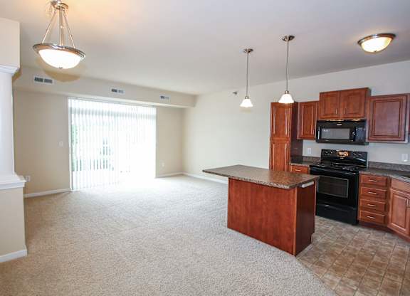 a kitchen with an island and a living room in the background