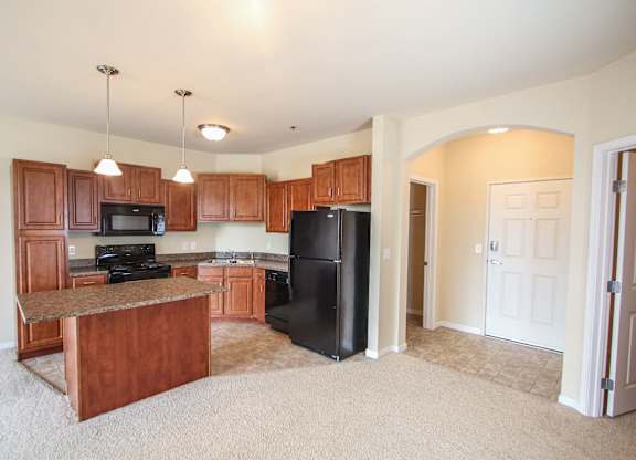 a kitchen with a black refrigerator freezer next to a stove top oven