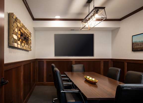 a conference room with a table and chairs and a tv on the wall  at Victoria Park and V2 Apartments, St. Paul, 55102