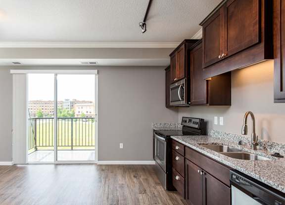 a kitchen with wood floors and a sliding glass door leading to a balcony  at Victoria Park and V2 Apartments, St. Paul