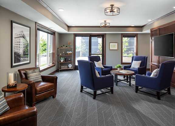 a community room filled with furniture and a large window  at Victoria Park and V2 Apartments, St. Paul, 55102