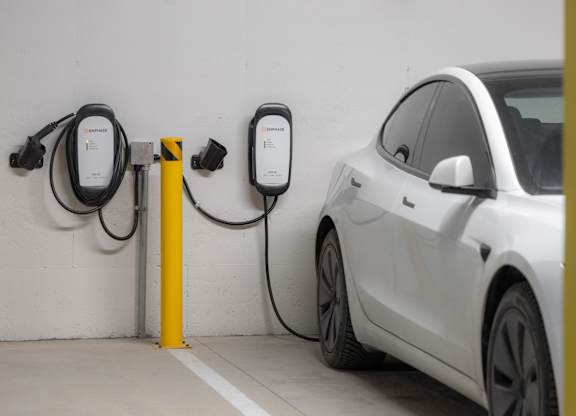 A white car is charging at a yellow charging station.