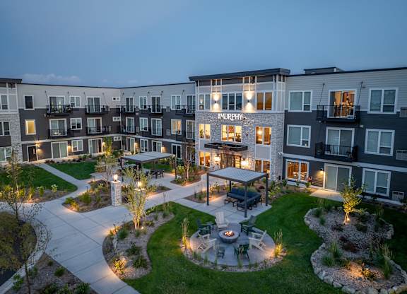 A courtyard with a fire pit surrounded by apartment buildings at dusk.