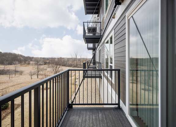 A balcony with a black railing and a glass door.
