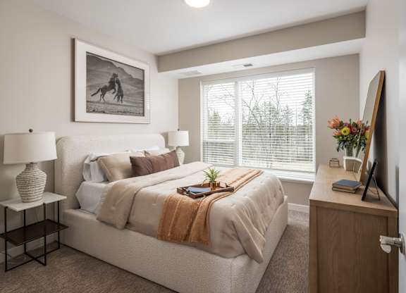 A bedroom with a bed, nightstand, and a painting on the wall.