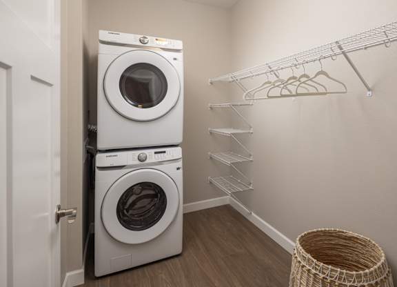 A laundry room with a white dryer and washer, a clothes rack and a basket.