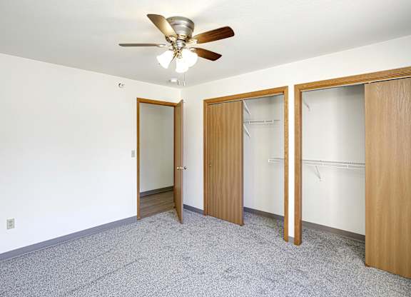 A room with a ceiling fan and three doors.