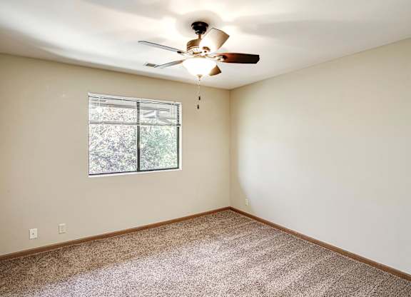 A room with a ceiling fan and carpeted floor.