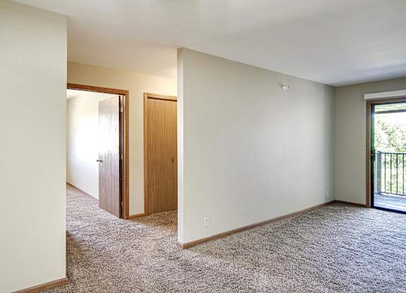 A room with a carpeted floor and a sliding glass door.