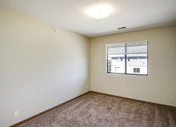 A room with a window and carpeted floor.