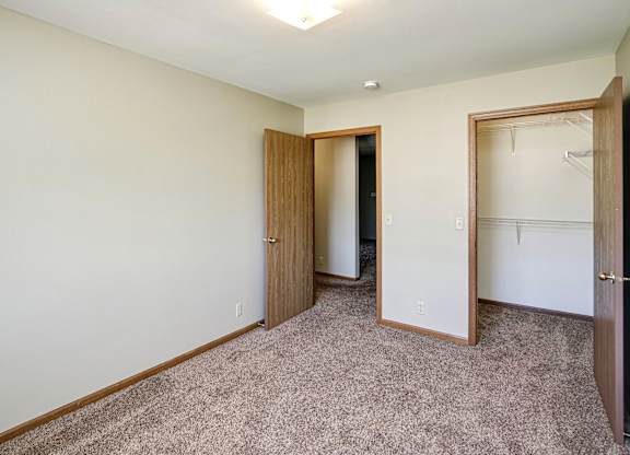 A room with a carpeted floor and two doors.
