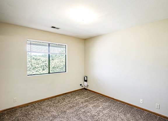 A room with a window and a carpeted floor.