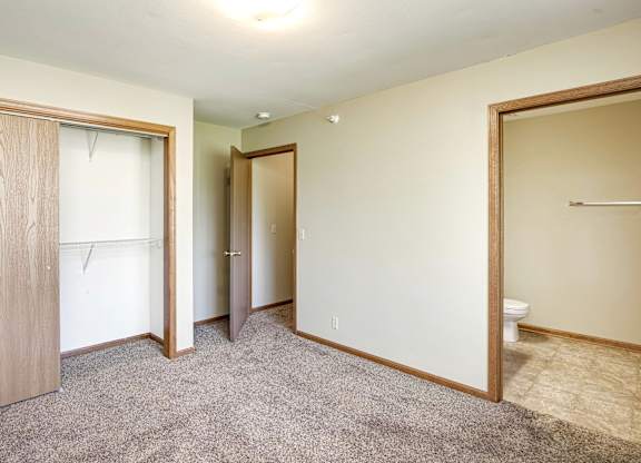 A room with a carpeted floor and a toilet in the corner.