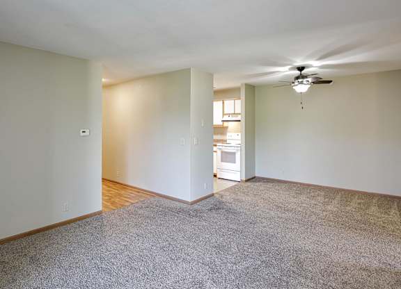 A room with a carpeted floor and a ceiling fan.
