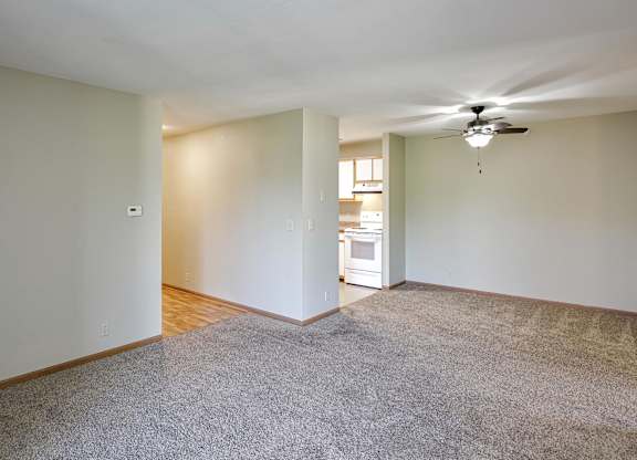 A room with a carpeted floor and a ceiling fan.