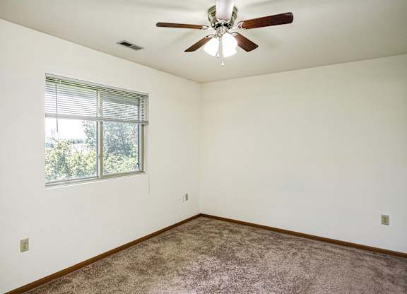 A room with a ceiling fan and a window with blinds.