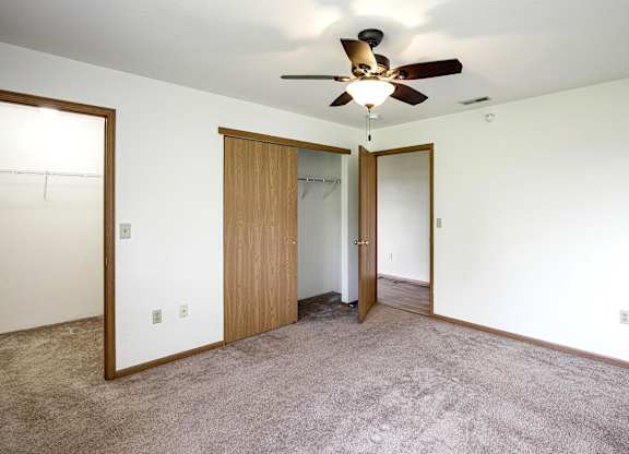 A room with a ceiling fan and carpeted floor.