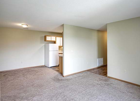 A room with a white fridge and a brown door.