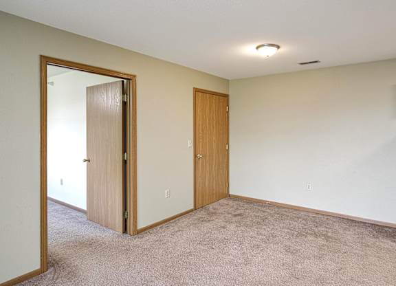 A room with a carpeted floor and two wooden doors.