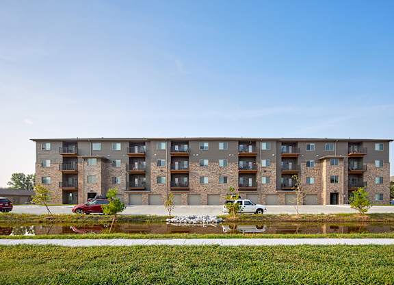 A modern apartment building with a parking lot in front.