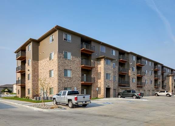 A large apartment building with a parking lot in front.