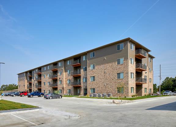 A large apartment building with a parking lot in front.