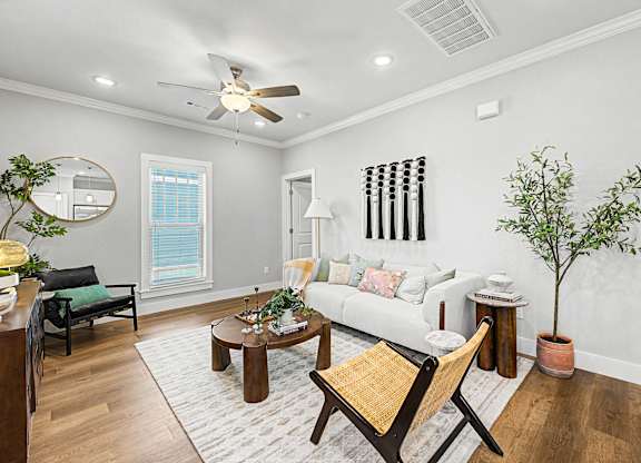 A living room with a white couch, a wooden chair, and a rug.