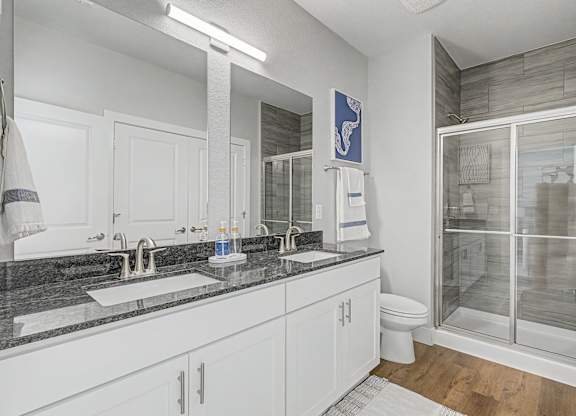 A modern bathroom with a glass shower stall and a marble countertop.