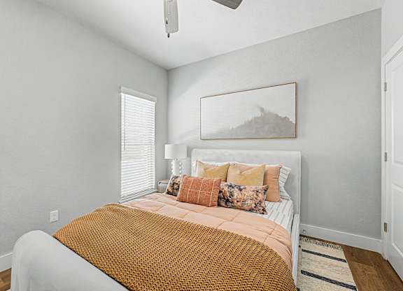 A bedroom with a bed, pillows, and a ceiling fan.