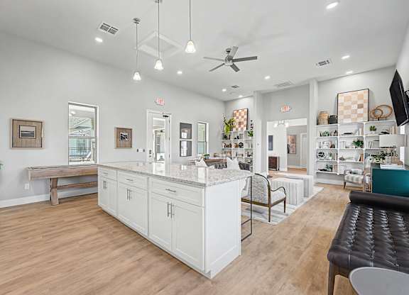 A well-lit, spacious kitchen and dining area with white cabinetry and a wooden floor.