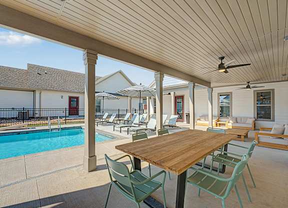 A wooden table is surrounded by chairs on a patio.