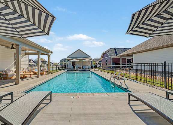 A pool surrounded by a black fence and striped umbrellas.