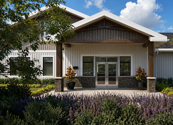 A modern house with a front yard and purple flowers.