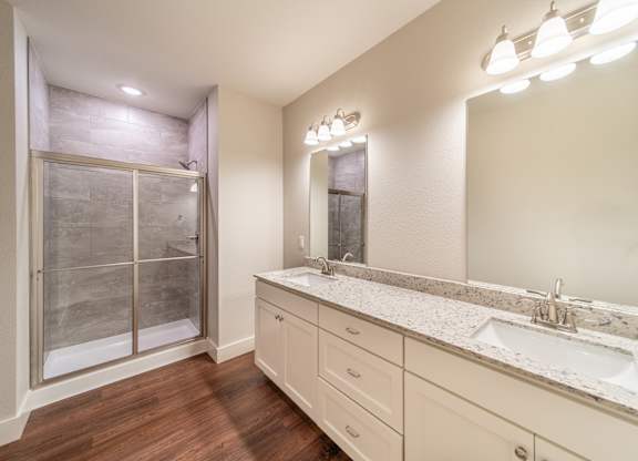 A bathroom with a sink, mirror, and a shower with a glass door.