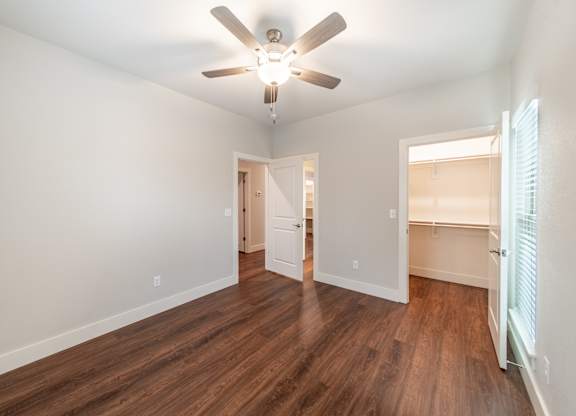 A room with a ceiling fan and wooden floors.