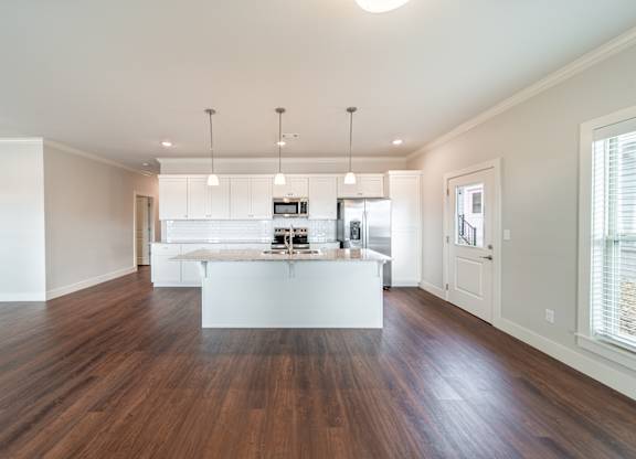 A kitchen with a white island and wooden floors.