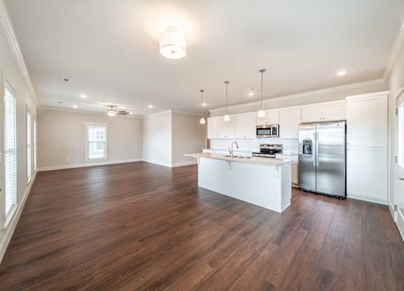 A kitchen with white cabinets and a wooden floor.