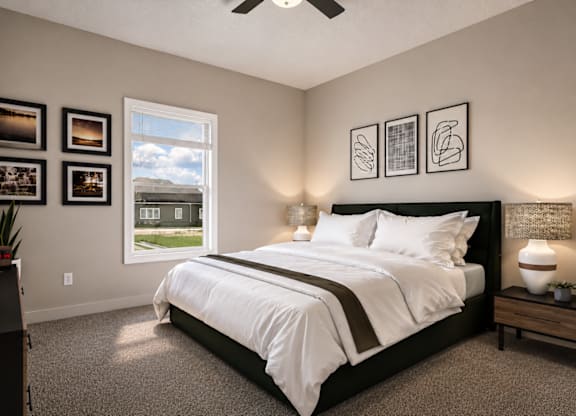 A bedroom with a large bed, a ceiling fan, and pictures on the wall.