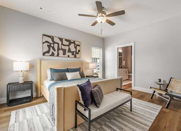A bedroom with a bed, a couch, and a ceiling fan.